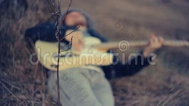 日落时分，一个男人躺在橡树下弹吉他
